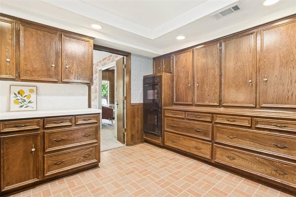 915 Grinnell Drive, Richardson, TX 75081 915 Grinnell Dr. - Kitchen featuring a tray ceiling with recessed lighting, a solar tube for additional natural light, traditional wood cabinetry with abundant storage, double ovens, and a large window above the kitchen sink.
