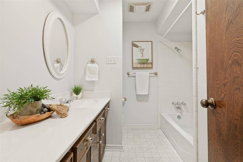 915 Grinnell Drive, Richardson, TX 75081 915 Grinnell Dr. - Bathroom featuring a large vanity cabinet with ample storage, single sink, and tub-and-shower combination.