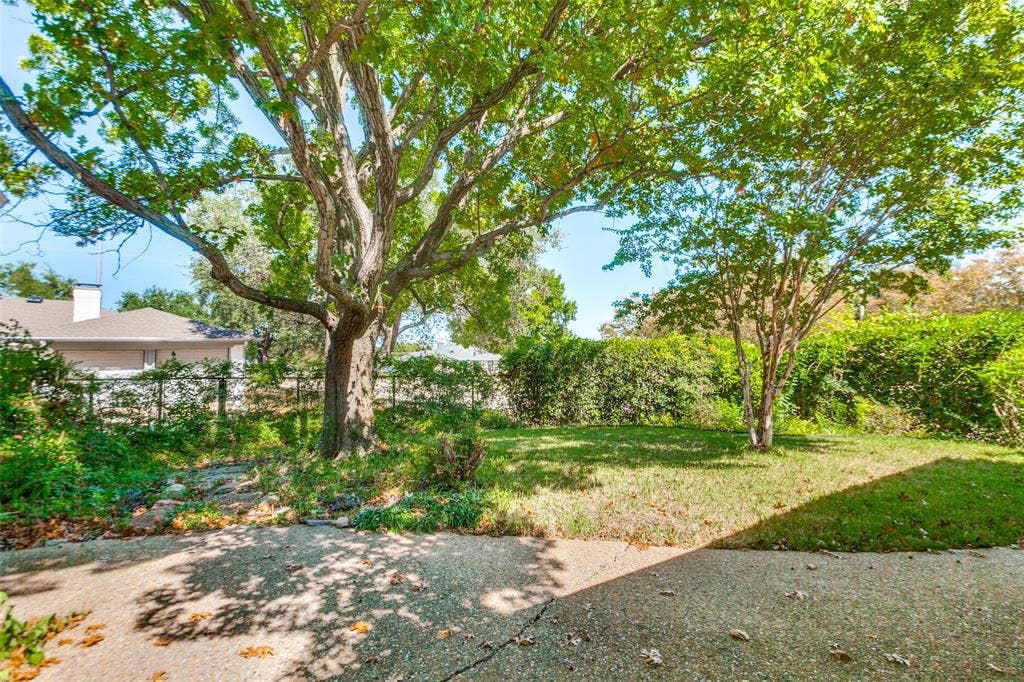915 Grinnell Drive, Richardson, TX 75081 915 Grinnell Dr. - Rear exterior of the home featuring mature trees, a covered back porch, and a private, established backyard setting.