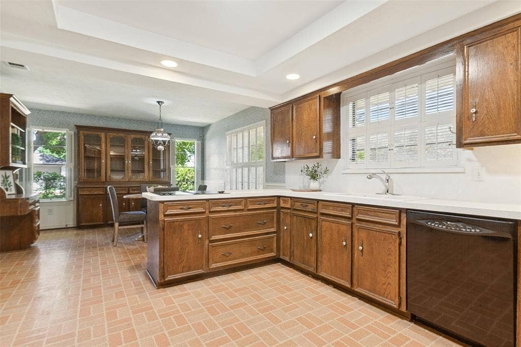 915 Grinnell Drive, Richardson, TX 75081 915 Grinnell Dr. - Kitchen featuring a tray ceiling with recessed lighting, a solar tube for additional natural light, traditional wood cabinetry with abundant storage, double ovens, and a large window above the kitchen sink.