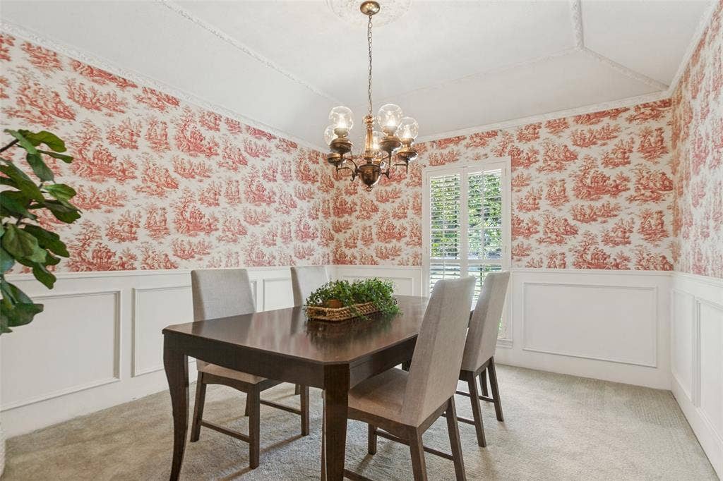 915 Grinnell Drive, Richardson, TX 75081 915 Grinnell Dr. - Formal dining area featuring half-height picture-frame wall molding, a gently sloped ceiling with elegant crown molding, and a window accented by a plantation shutter.