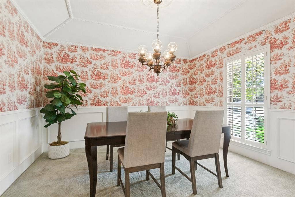 915 Grinnell Drive, Richardson, TX 75081 915 Grinnell Dr. - Formal dining area featuring half-height picture-frame wall molding, a gently sloped ceiling with elegant crown molding, and a window accented by a plantation shutter.