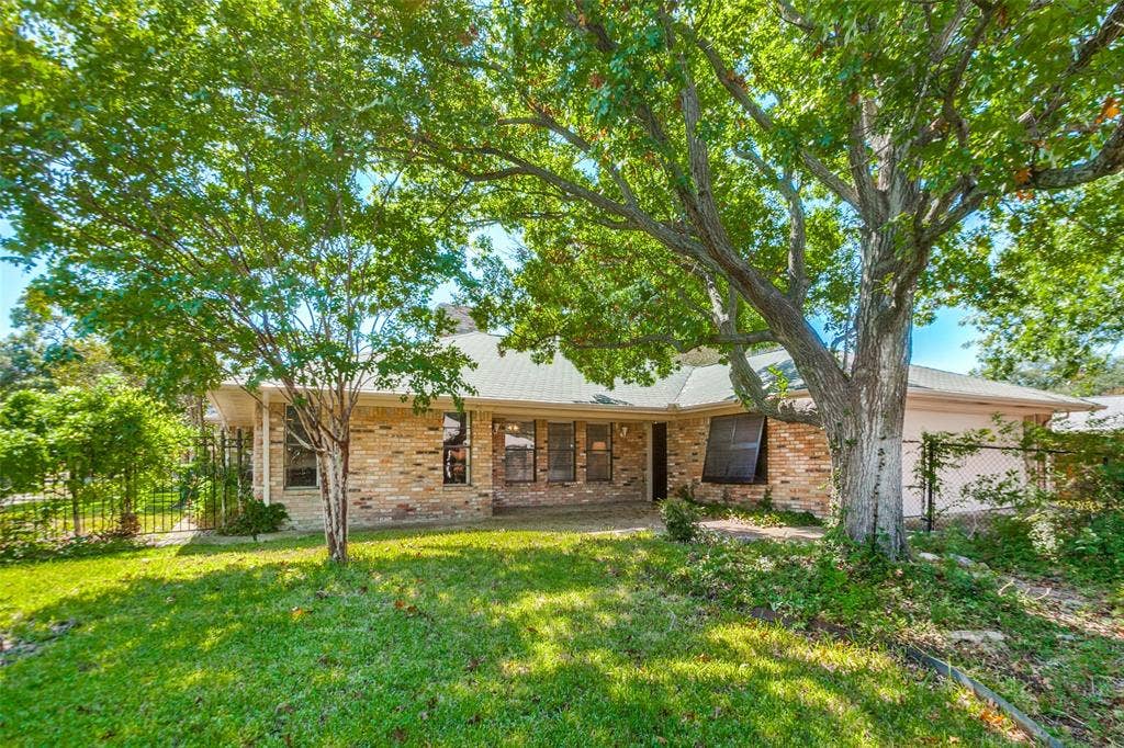 915 Grinnell Drive, Richardson, TX 75081 915 Grinnell Dr. - Rear exterior of the home featuring mature trees, a covered back porch, and a private, established backyard setting.