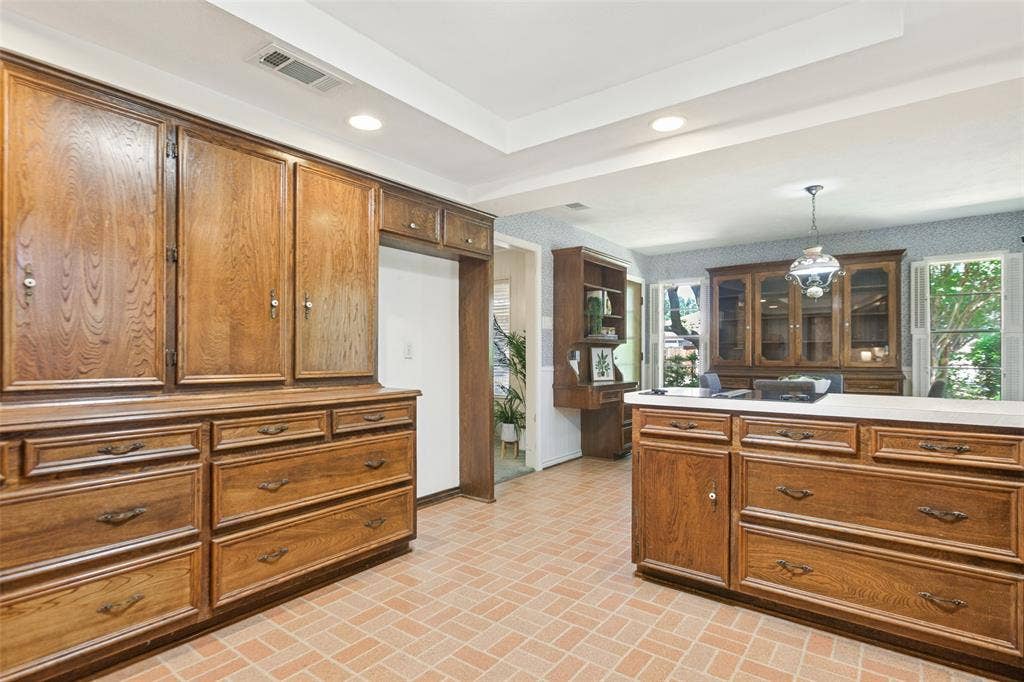 915 Grinnell Drive, Richardson, TX 75081 915 Grinnell Dr. - Kitchen featuring a tray ceiling with recessed lighting, a solar tube for additional natural light, traditional wood cabinetry with abundant storage, double ovens, and a large window above the kitchen sink.