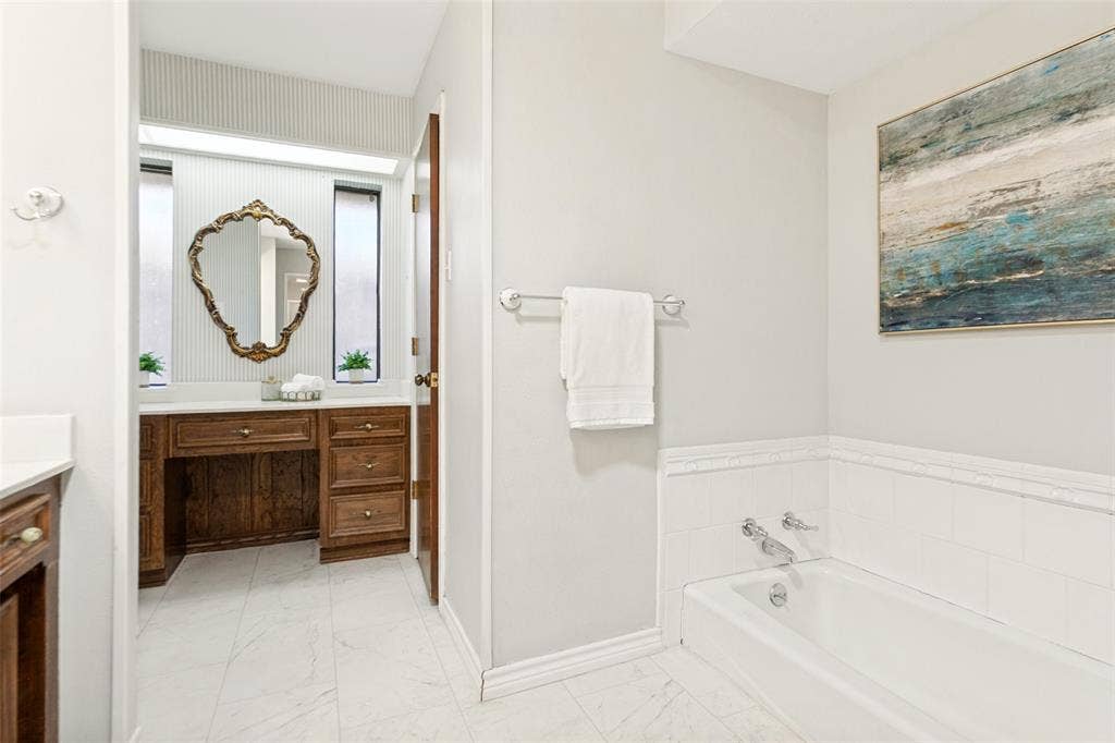 915 Grinnell Drive, Richardson, TX 75081 915 Grinnell Dr. - Elegant primary bathroom featuring a sit-down vanity, large dual-sink vanity, sunken soaking tub, separate shower, and access to two spacious walk-in closets.