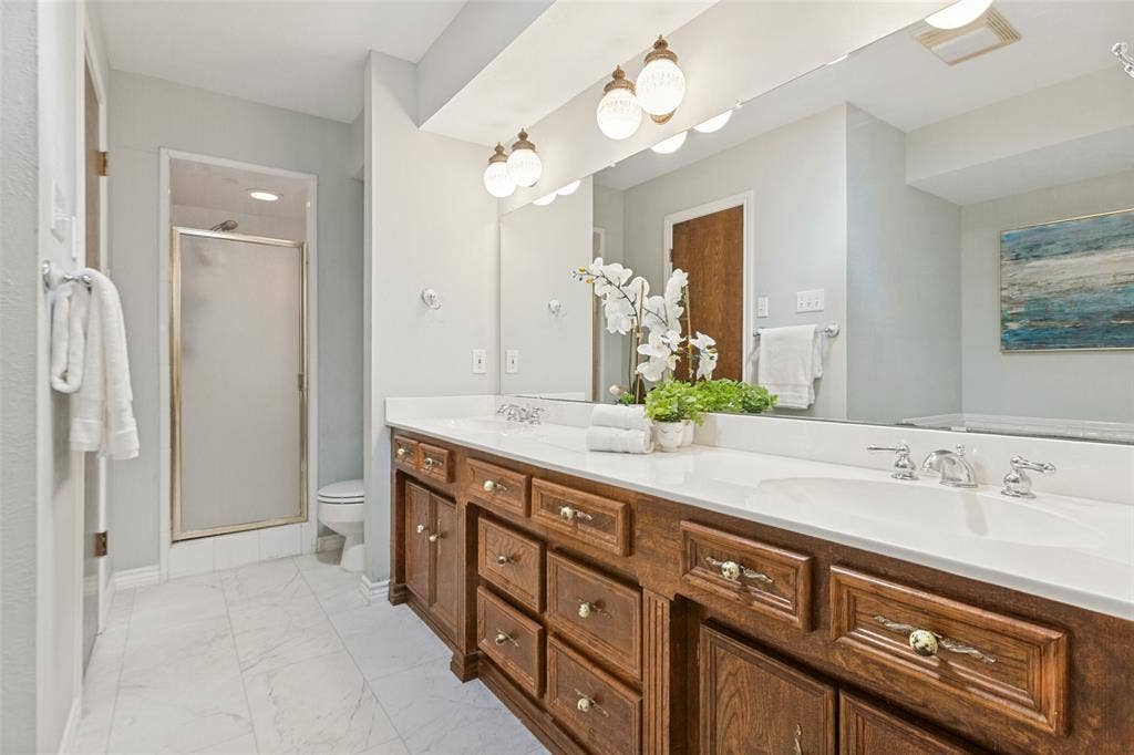 915 Grinnell Drive, Richardson, TX 75081 915 Grinnell Dr. - Elegant primary bathroom featuring a sit-down vanity, large dual-sink vanity, sunken soaking tub, separate shower, and access to two spacious walk-in closets.