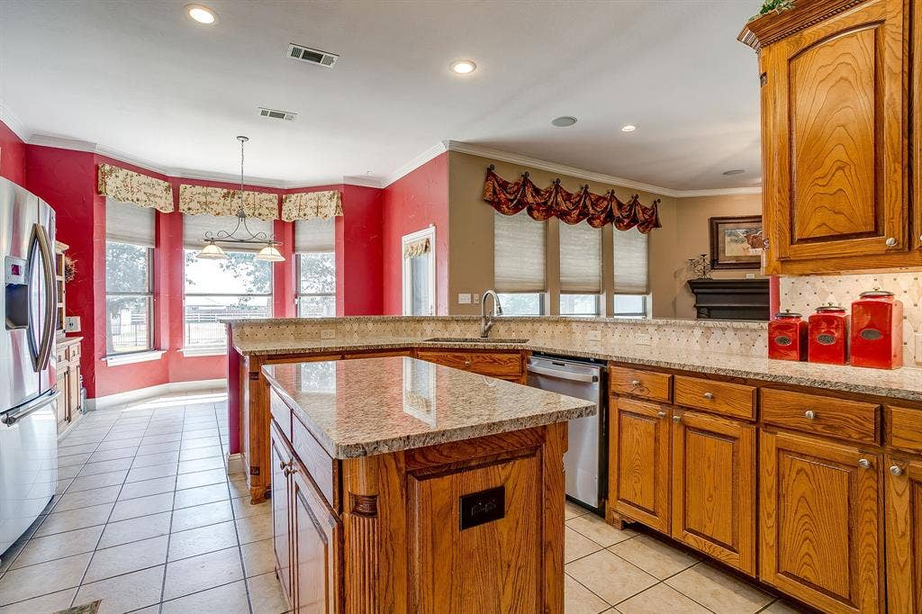 Kitchen featuring granite countertops, wood cabinetry, stainless steel refrigerator, white tile flooring, and recessed lighting