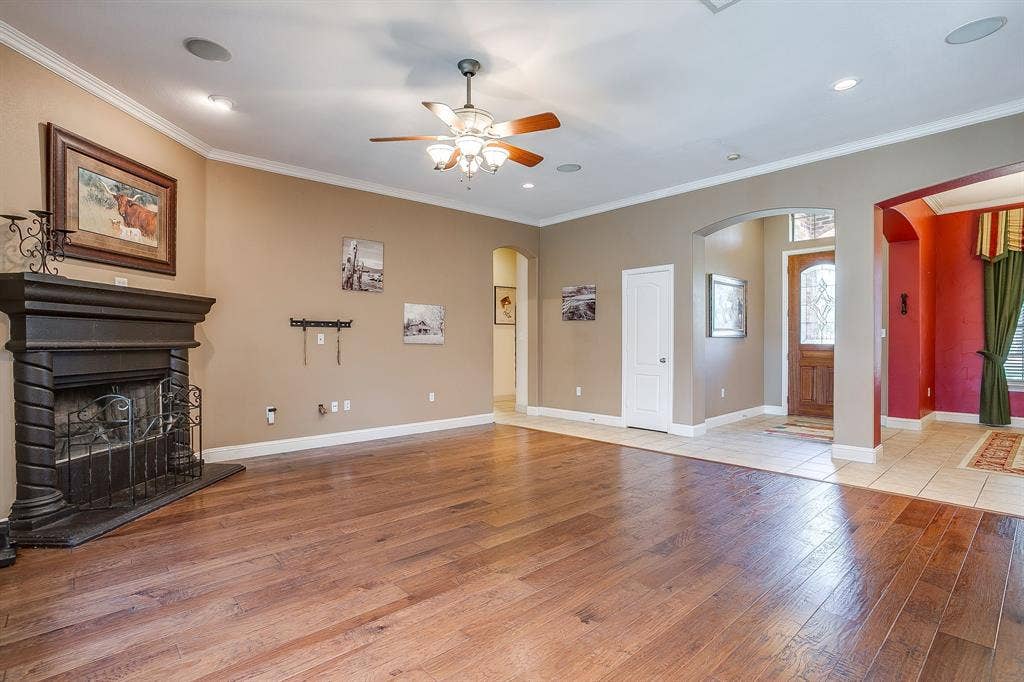 Hardwood flooring, crown molding, built-in fireplace, ceiling fan, and recessed lighting
