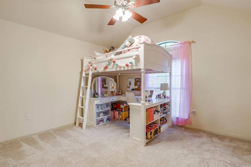 Vaulted ceiling with a ceiling fan, carpet flooring, and a large window with blinds