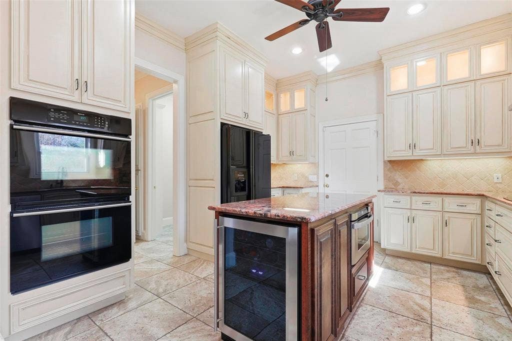 5949 River Bend Drive, Benbrook, TX 76132 Kitchen featuring an integrated double oven, a central island with a wine refrigerator, ample cabinetry with glass-front uppers, a tiled backsplash, and recessed lighting