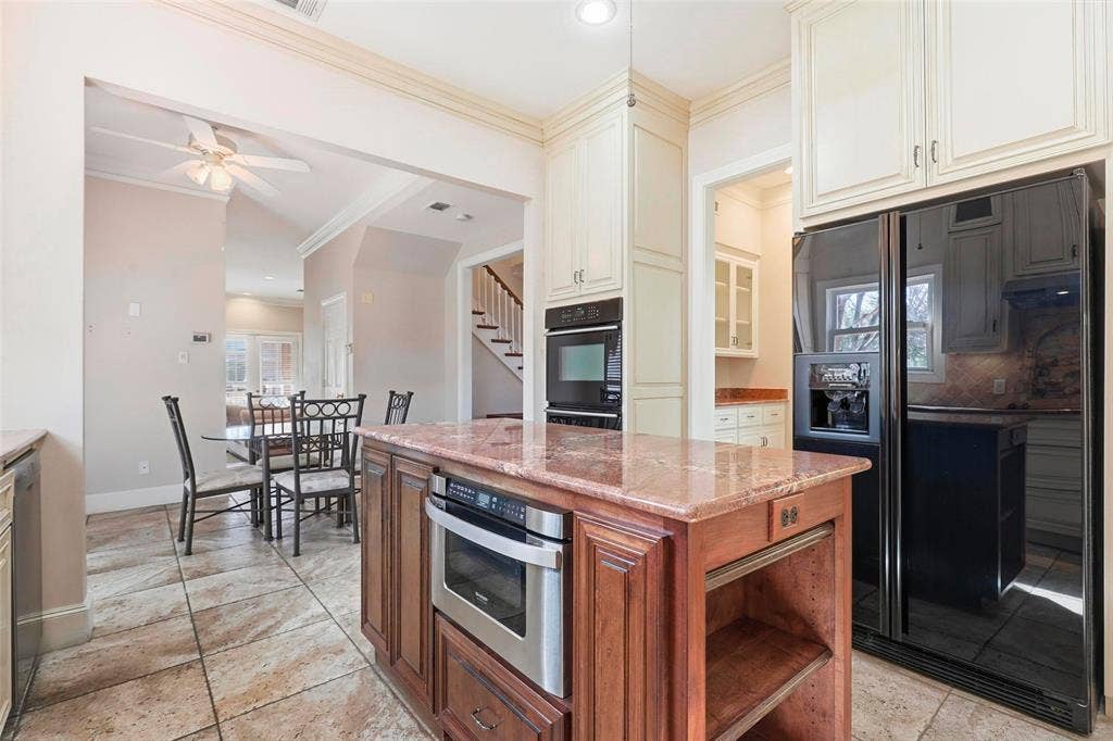 5949 River Bend Drive, Benbrook, TX 76132 Kitchen featuring a large central island with a built-in microwave, integrated double oven, cream-colored cabinetry, and a black French door refrigerator