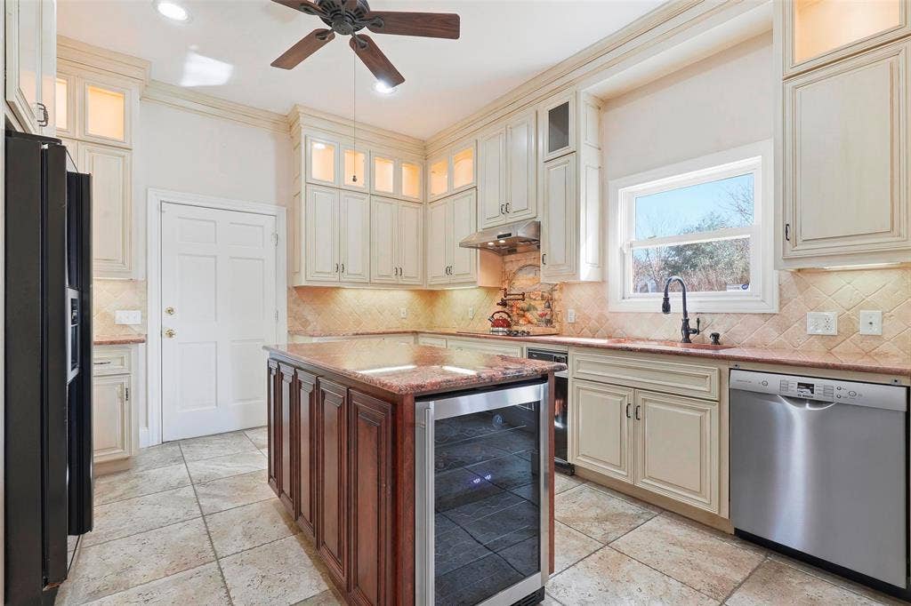 5949 River Bend Drive, Benbrook, TX 76132 Kitchen with light-colored cabinetry, a central island with a built-in beverage cooler, stainless steel appliances, a tile backsplash, and a ceiling fan