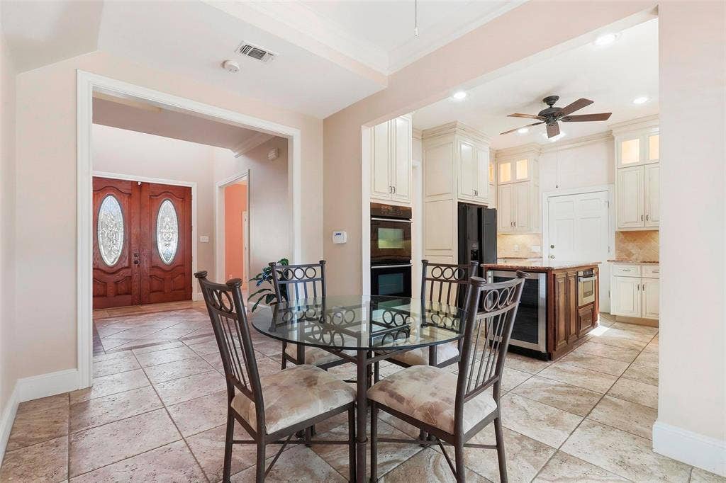 5949 River Bend Drive, Benbrook, TX 76132 Spacious kitchen featuring cream cabinetry, built-in double ovens, and an island with an integrated beverage refrigerator
