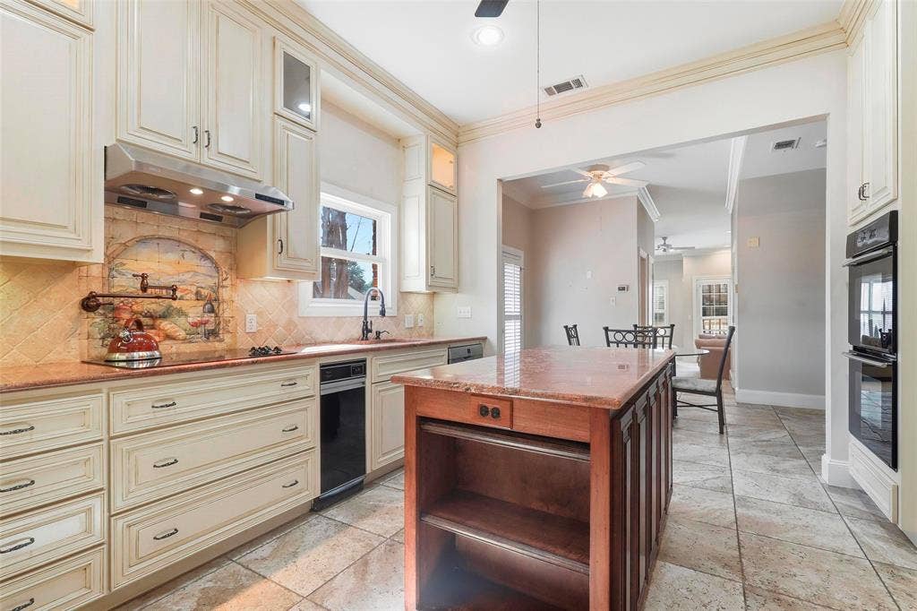 5949 River Bend Drive, Benbrook, TX 76132 Cream-toned cabinetry, built-in double ovens, and a central kitchen island with a stone countertop