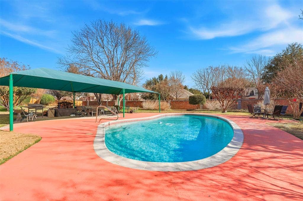 5949 River Bend Drive, Benbrook, TX 76132 Freeform swimming pool with a white coping and vibrant red concrete decking