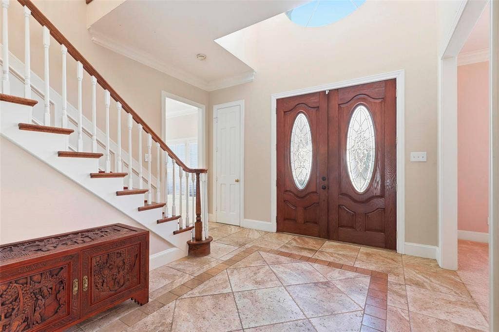5949 River Bend Drive, Benbrook, TX 76132 Double entry doors with decorative oval glass inserts, two-story foyer, tiled flooring with a decorative border, and a wood-tread staircase with white risers and balusters