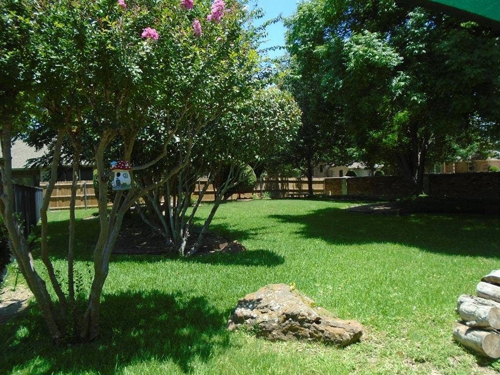 5949 River Bend Drive, Benbrook, TX 76132 Spacious backyard featuring a lush green lawn, mature trees, and a privacy fence