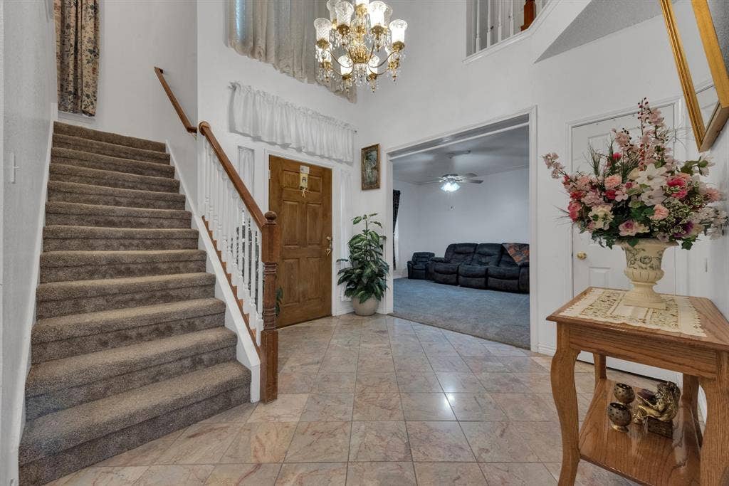 4622 Devonshire Drive, Grand Prairie, TX 75052 Spacious entryway featuring tile flooring, a carpeted staircase with wood handrails, and a grand chandelier