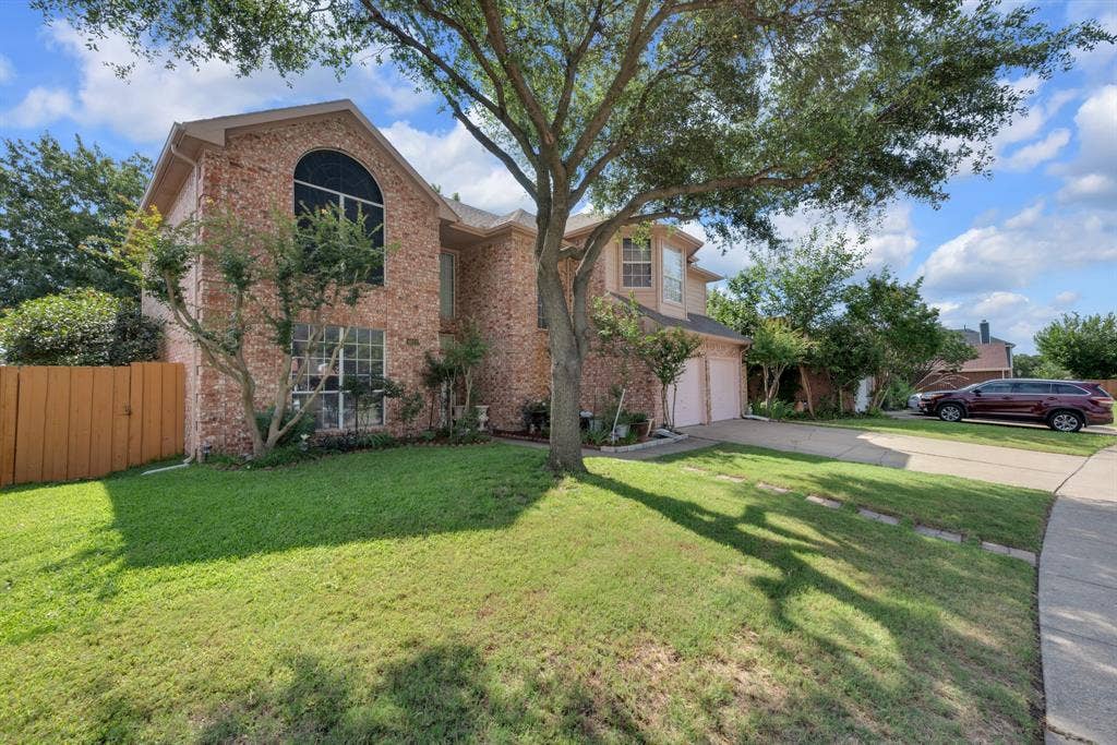 4622 Devonshire Drive, Grand Prairie, TX 75052 Brick-clad exterior with a prominent arched window, a two-car garage, and mature front yard landscaping