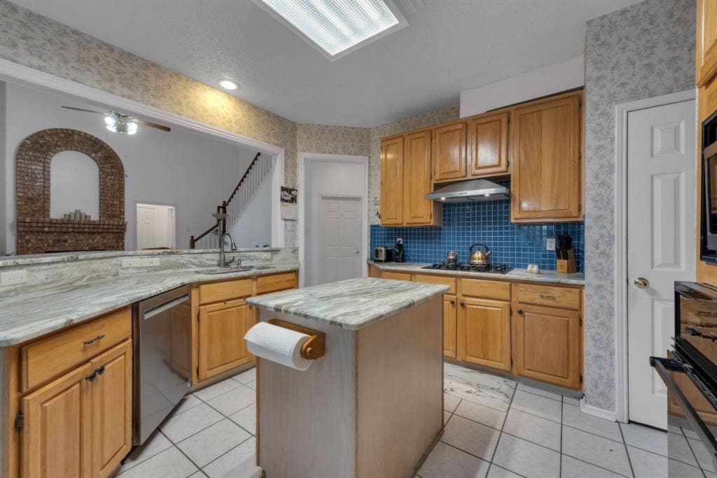 4622 Devonshire Drive, Grand Prairie, TX 75052 Kitchen featuring a central island, light wood cabinetry, stone countertops, and a blue tile backsplash