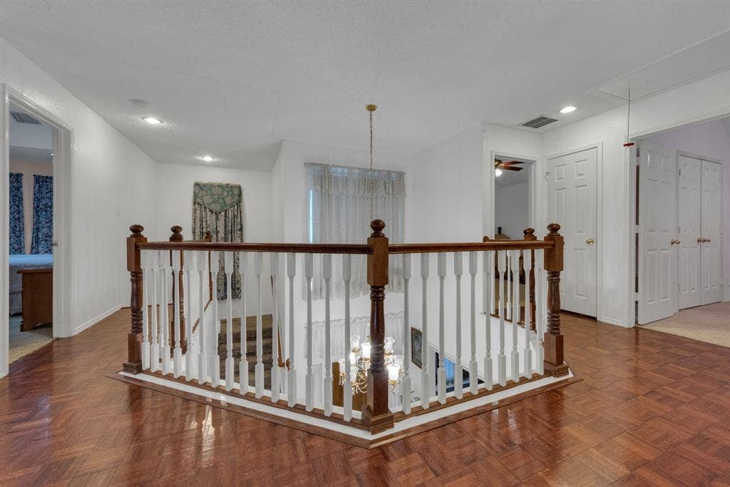 4622 Devonshire Drive, Grand Prairie, TX 75052 Upper-level landing featuring wood-finish parquet flooring, white walls, and a wooden banister with white spindles overlooking the staircase