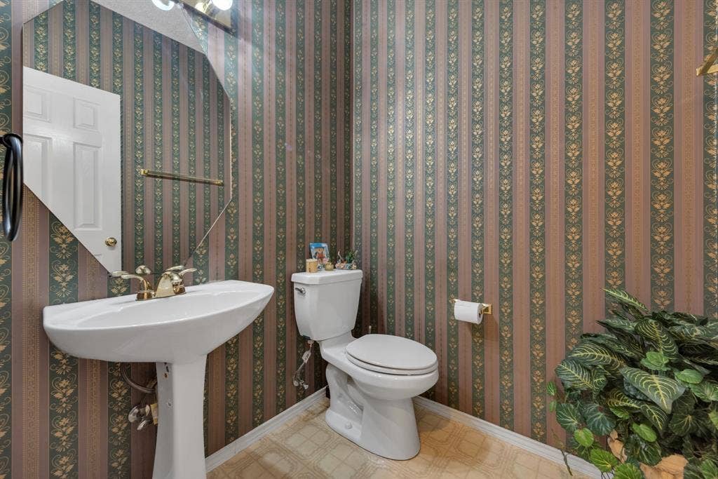 4622 Devonshire Drive, Grand Prairie, TX 75052 Pedestal sink with brass-finish faucet, an octagonal mirror, and patterned wallpaper
