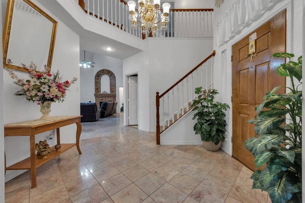 4622 Devonshire Drive, Grand Prairie, TX 75052 Two-story foyer featuring tile flooring, a prominent wooden staircase with white balusters, and an elegant chandelier