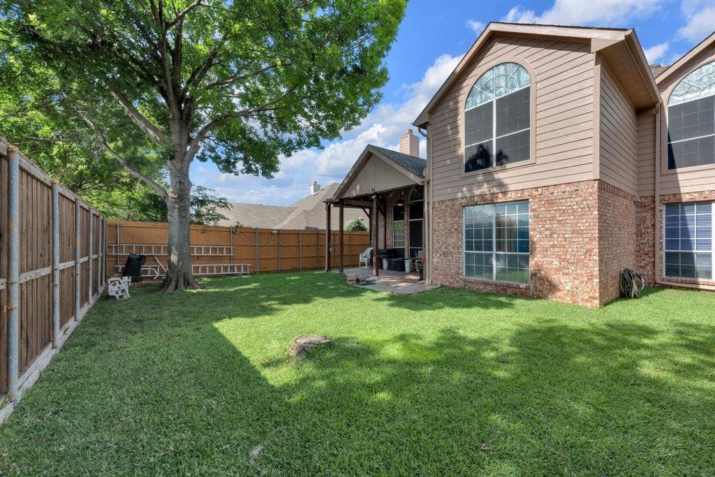 4622 Devonshire Drive, Grand Prairie, TX 75052 Spacious backyard featuring a manicured lawn, a mature tree, and a covered patio area