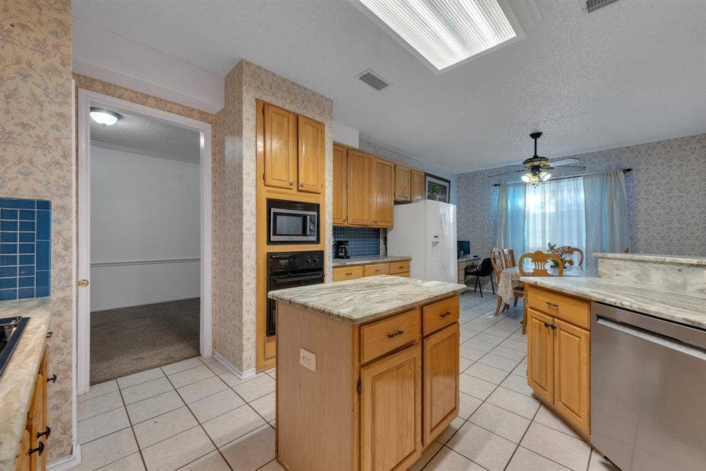 4622 Devonshire Drive, Grand Prairie, TX 75052 Kitchen featuring wood cabinetry, light-toned countertop surfaces, and a central island