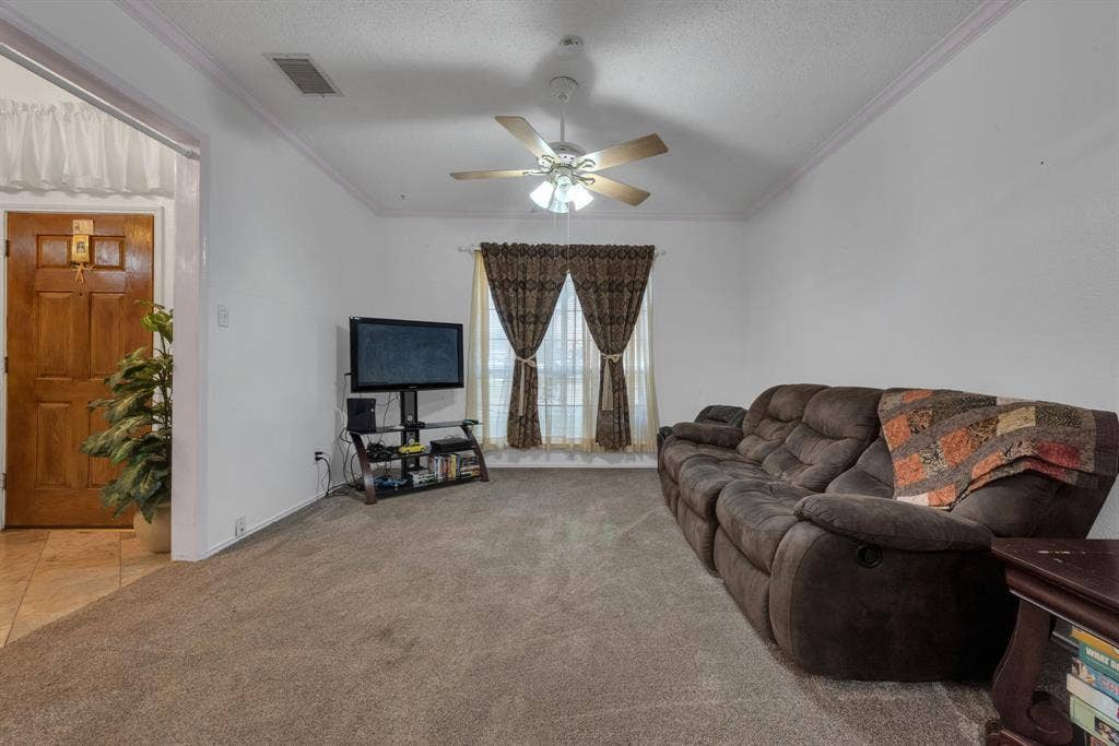 4622 Devonshire Drive, Grand Prairie, TX 75052 Carpeted living area featuring a vaulted ceiling with crown molding, a ceiling fan, and a window with blinds