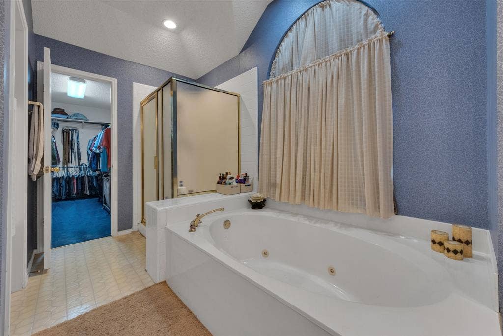 4622 Devonshire Drive, Grand Prairie, TX 75052 Spacious bathroom featuring a built-in jetted tub with brass fixtures, an adjacent walk-in shower with gold-toned framing, and an arched window