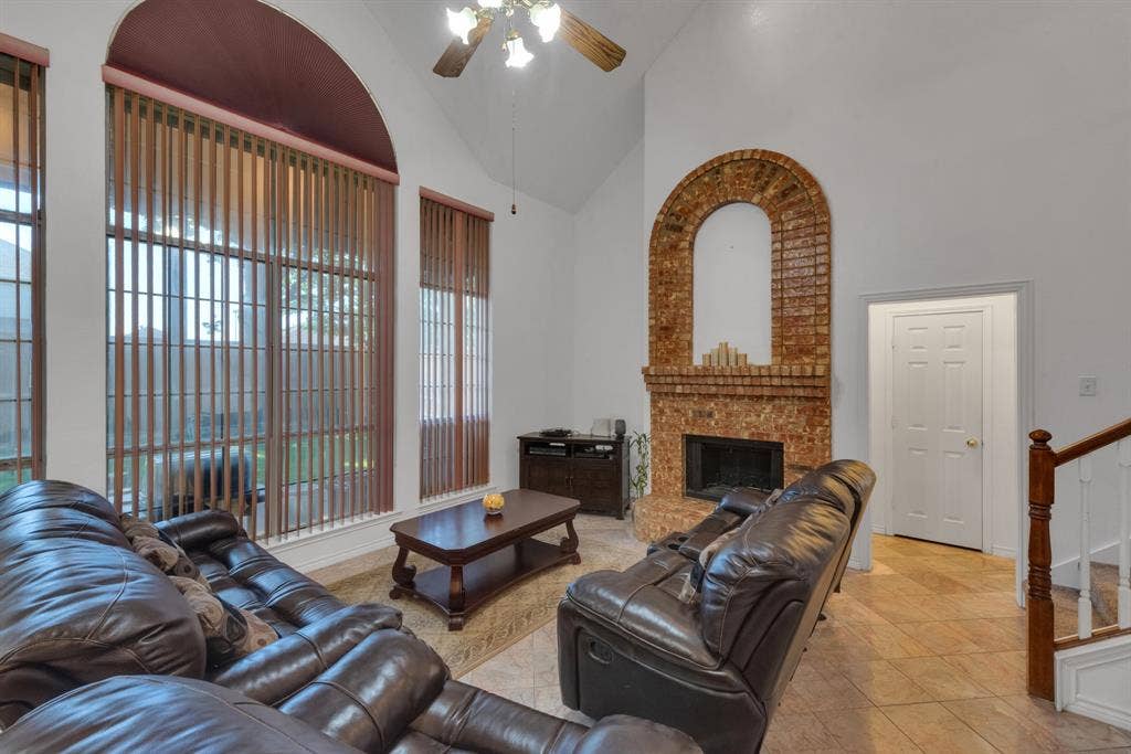 4622 Devonshire Drive, Grand Prairie, TX 75052 Vaulted ceiling living area featuring an arched brick fireplace, large arched window, and tile flooring