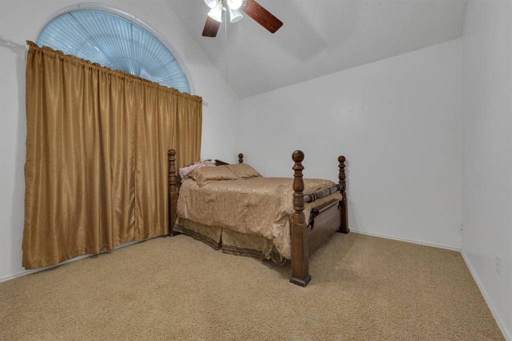 4622 Devonshire Drive, Grand Prairie, TX 75052 Vaulted ceiling room featuring a large arched window, a ceiling fan, and carpeted flooring