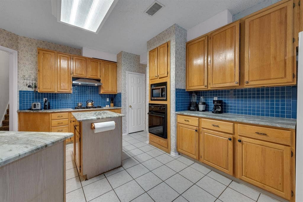 4622 Devonshire Drive, Grand Prairie, TX 75052 Kitchen featuring wood cabinetry, blue tiled backsplash, built-in oven, and a center island with a stone-finish countertop