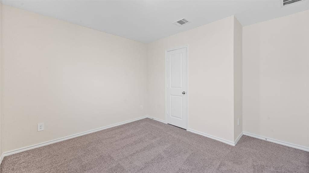 Carpeted room featuring light beige walls, white baseboards, and a white two-panel door with a round knob