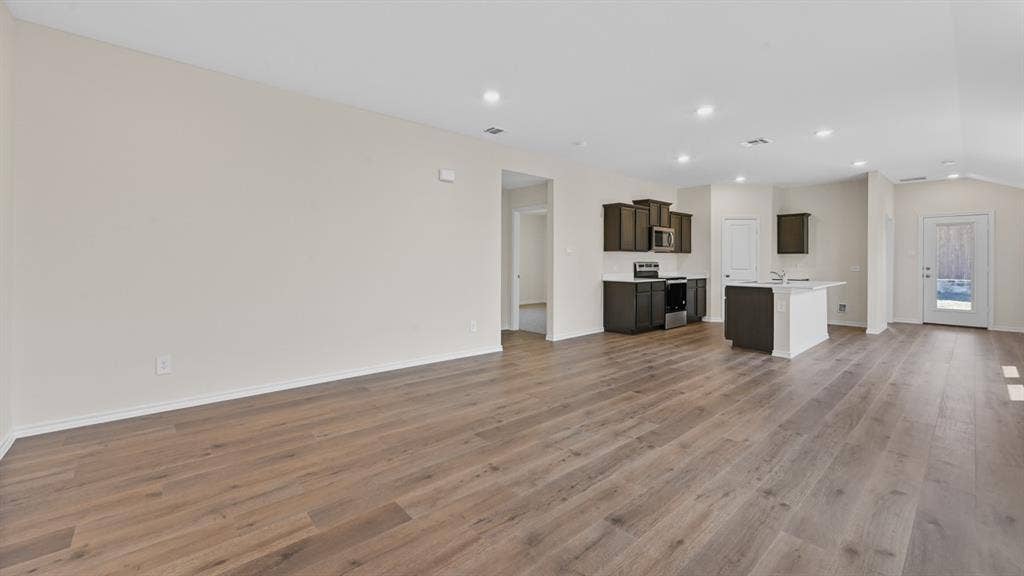 Open-concept living area featuring wood-finish flooring, recessed lighting, and vaulted ceilings