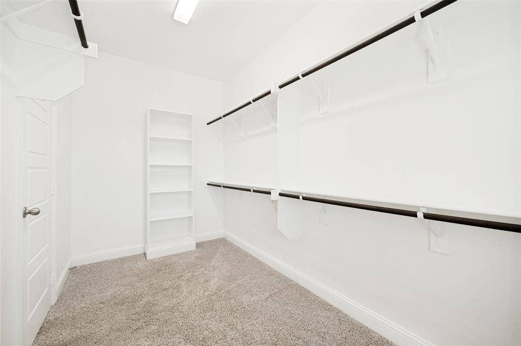 12986 Jk Ojha Street, Farmers Branch, TX 75234 Walk-in closet featuring light grey carpet, white walls, and a five-shelf white built-in bookcase