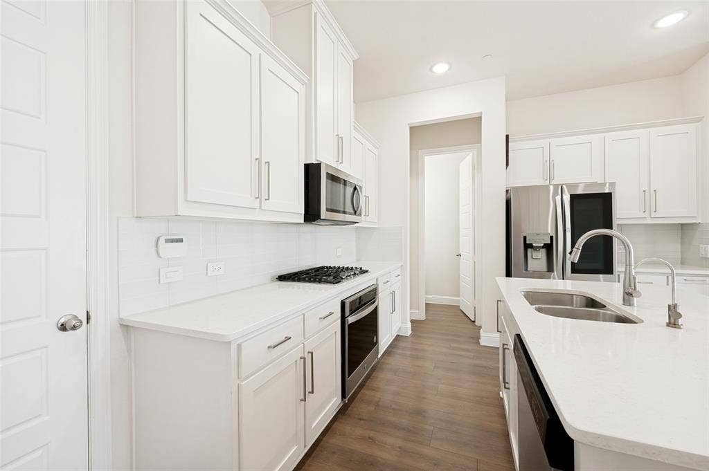 12986 Jk Ojha Street, Farmers Branch, TX 75234 Modern kitchen featuring white shaker cabinetry, white subway tile backsplash, stainless steel appliances, and a double basin sink with a gooseneck faucet