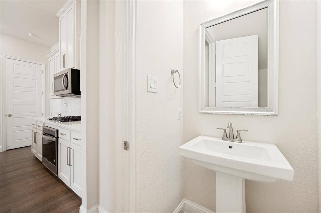 12986 Jk Ojha Street, Farmers Branch, TX 75234 Pedestal sink with a framed mirror and brushed nickel fixtures