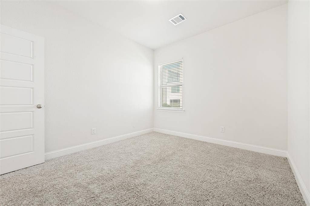 12986 Jk Ojha Street, Farmers Branch, TX 75234 Bright room featuring light-colored carpeting, white baseboards, and a window with horizontal blinds