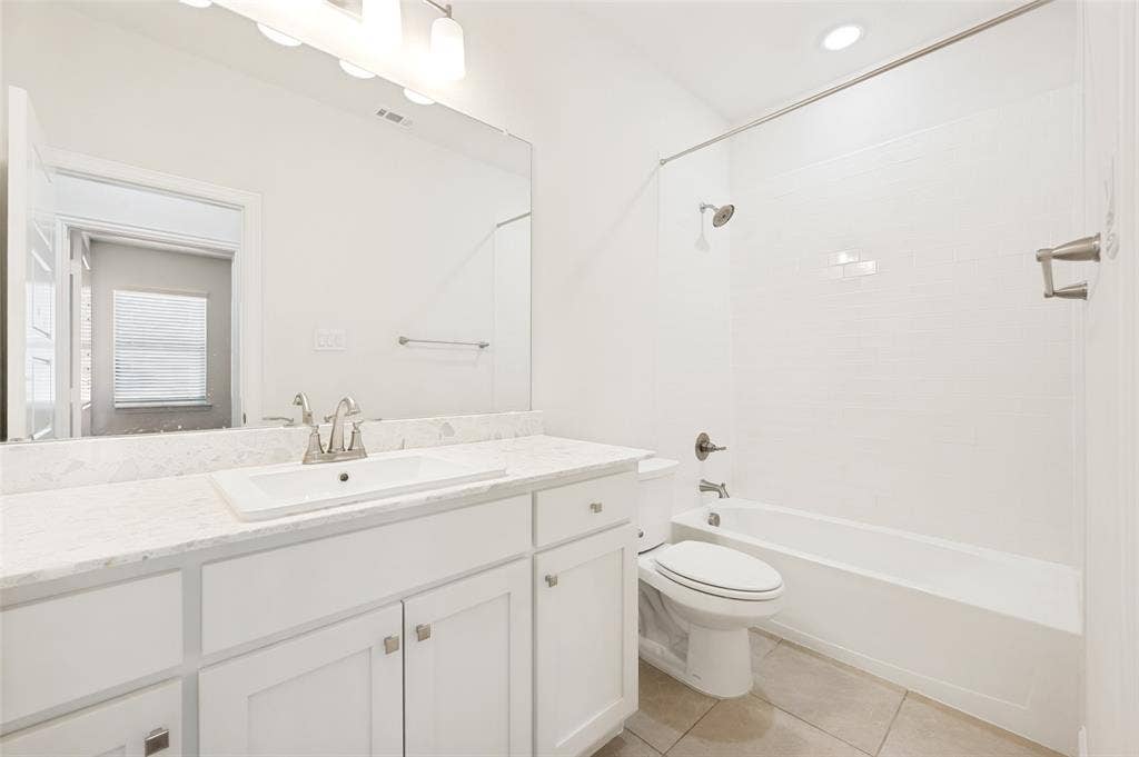12986 Jk Ojha Street, Farmers Branch, TX 75234 Bathroom featuring a white vanity with an undermount sink, a light-toned countertop, a large wall-mounted mirror, and a shower-over-tub combination with subway tile surround