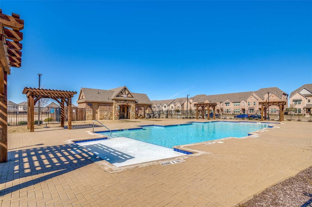 12986 Jk Ojha Street, Farmers Branch, TX 75234 Community pool featuring a stone and brick clubhouse building, multiple pergola structures, and a surrounding paved deck