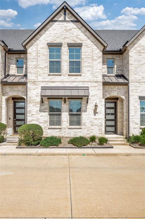 12986 Jk Ojha Street, Farmers Branch, TX 75234 Contemporary multi-level townhome featuring a light brick exterior and dark shingle roof