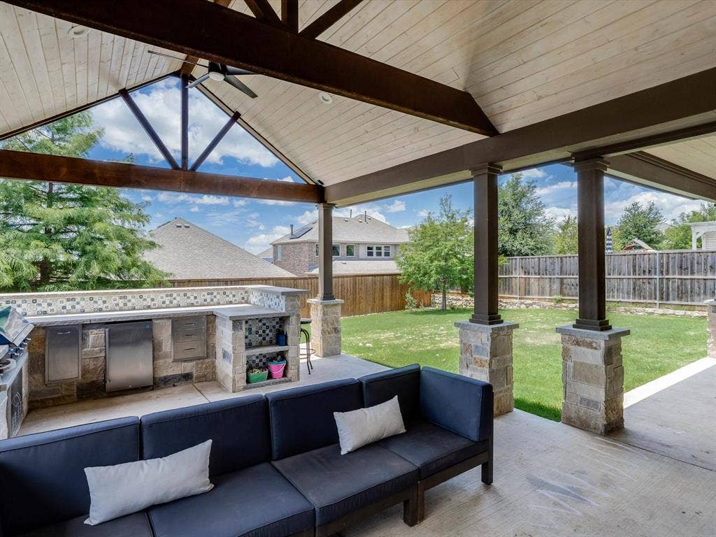 1021 Daylily Drive, Northlake, TX 76226 Expansive covered patio featuring a vaulted wood-plank ceiling, exposed wood beams, and a ceiling fan