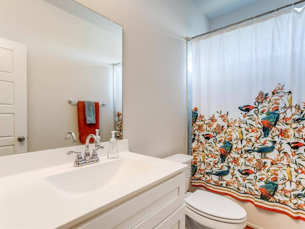 1021 Daylily Drive, Northlake, TX 76226 Bathroom featuring a white vanity with integrated sink, chrome faucet, and expansive wall mirror