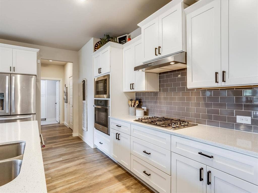 1021 Daylily Drive, Northlake, TX 76226 Kitchen featuring white cabinetry, stainless steel appliances, a subway tile backsplash, light-colored countertops, and wood-finish flooring