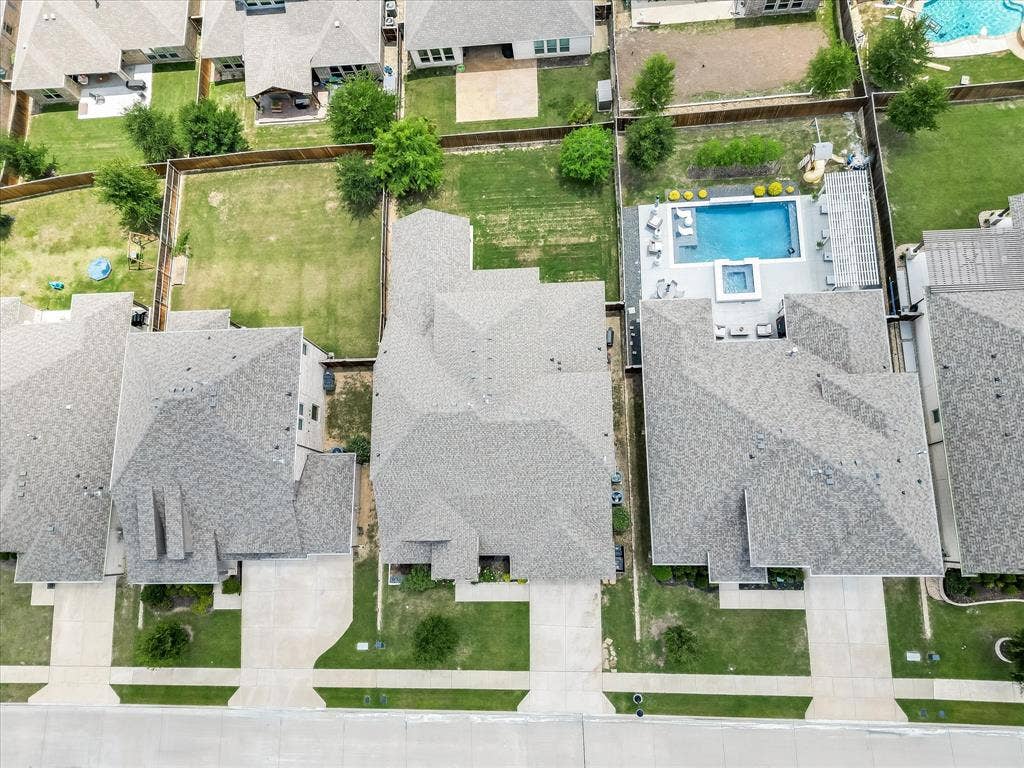 1021 Daylily Drive, Northlake, TX 76226 Aerial view showcasing the property's gray shingle roof, concrete driveway, and a fenced backyard with green lawn