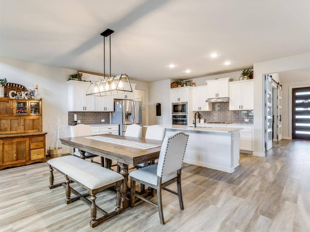 1021 Daylily Drive, Northlake, TX 76226 Expansive kitchen and dining area featuring light wood-finish flooring, white cabinetry, stainless steel appliances, a tiled backsplash, and recessed lighting