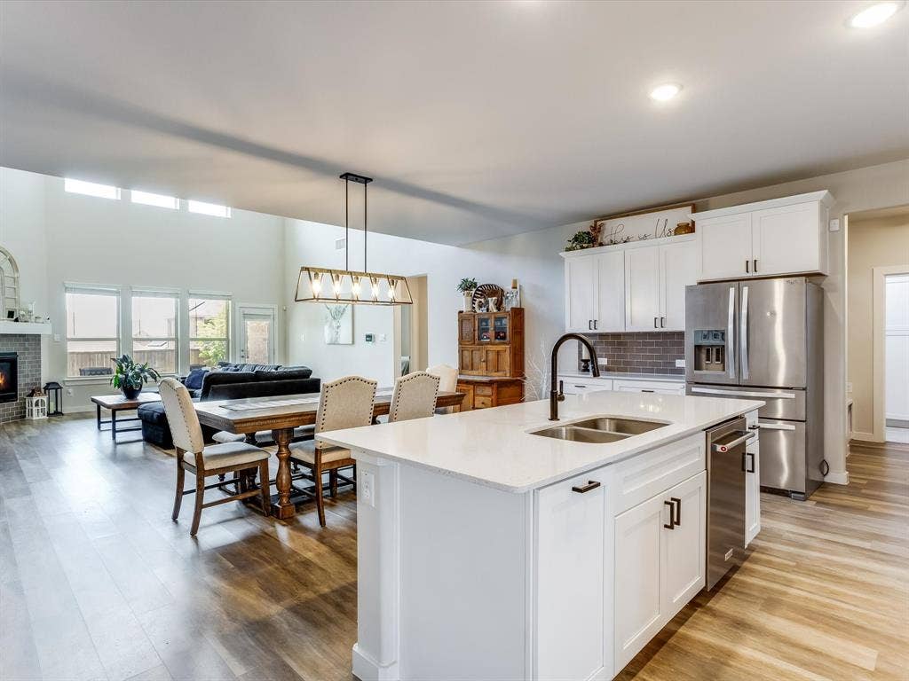 1021 Daylily Drive, Northlake, TX 76226 Open-concept living space featuring a central kitchen island with a double basin sink, white cabinetry, and stainless steel appliances