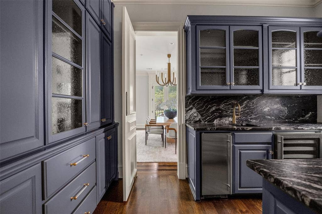 Custom cabinetry in a rich blue hue featuring glass-front uppers and polished hardware